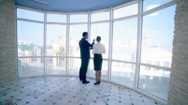 İşadamları erkek ve kadın temiz panoramik pencere yakınında modern bir ofis binasında iş projesi tartışmak. İş konsepti. Steadicam ateş.