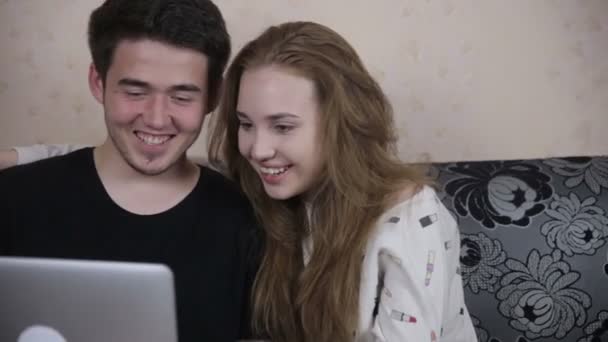 Feliz sorrindo casal usando o laptop sentado no sofá em casa . — Vídeo de Stock