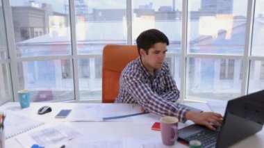 Kendinden emin ve çekici işadamı çizimlerle çalışma planları hafif, modern bir ofiste. İş kavramı.