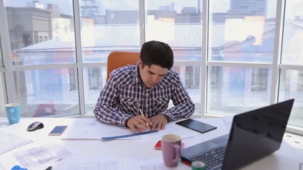 Ein selbstbewusster und attraktiver Geschäftsmann, der mit Zeichnungen, Entwürfen in einem hellen, modernen Büro arbeitet. Geschäftskonzept. — Stockvideo