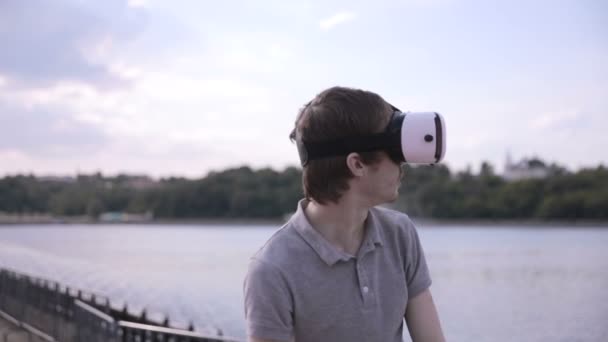 Joven hombre guapo con gafas de realidad virtual en una ciudad . — Vídeos de Stock