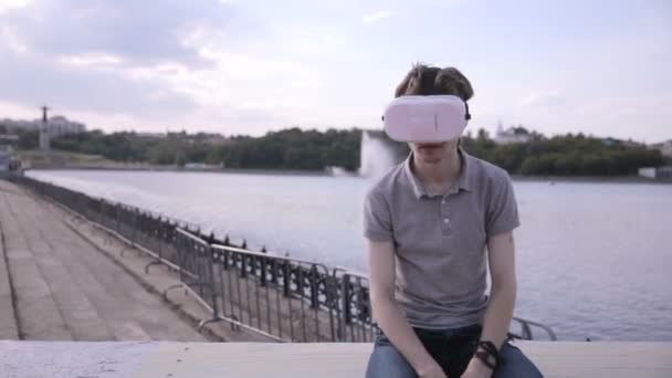 Joven hombre guapo con gafas de realidad virtual en una ciudad . — Vídeos de Stock