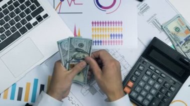 Tanınmayan işadamı yüz dolar faturaları masanın üzerine böler. Ateş yukarıda Üstten Görünüm.