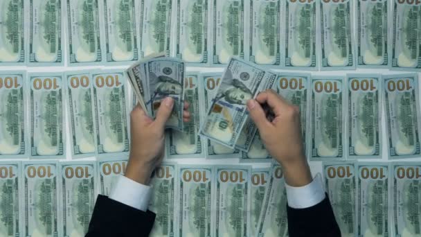 Een businessmans handen tellen honderd ons dollarbiljetten aan een tafel. Achtergrond van de dollar. — Stockvideo