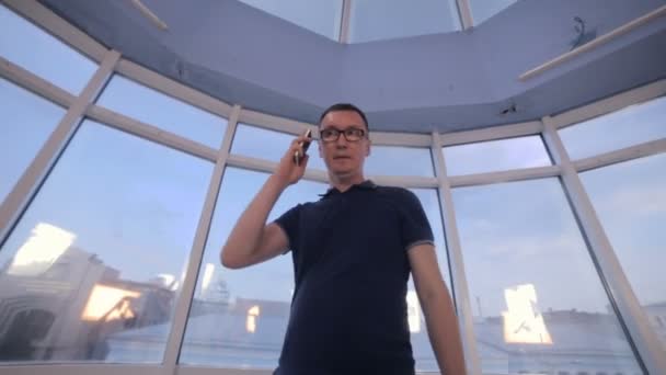 Jonge man in moderne lichte kantoren praten aan de telefoon. Steadicam schot. — Stockvideo