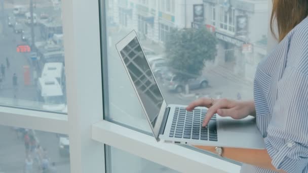 Kvinna som använder bärbar dator nära panoramafönstret i moderna ljusa kontor. — Stockvideo