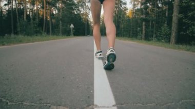 Atletik youg kadın bir parkta koşu. Koşu ayakkabıları ve bacak eylem kapatın. Stedycam atış.