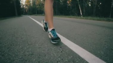 Atletik youg kadın bir parkta koşu. Koşu ayakkabıları ve bacak eylem kapatın. Stedycam atış.