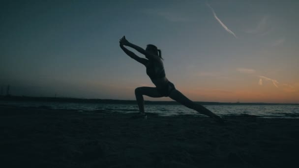 Mladá žena dělá gymnastiku při západu slunce. Zpomalený pohyb. — Stock video