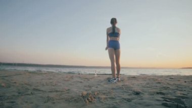 İnce bir rakam olan kadın jimnastik güneş doğarken devreye girer. Ağır çekim. 100 fps.