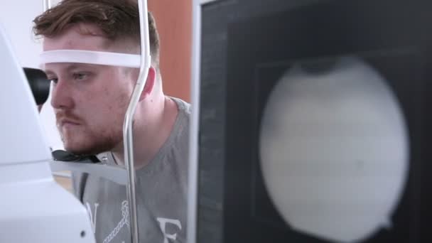 Paziente maschio in visita oculistica. Frequenza medica presso l'optometrista in una luminosa clinica moderna . — Video Stock