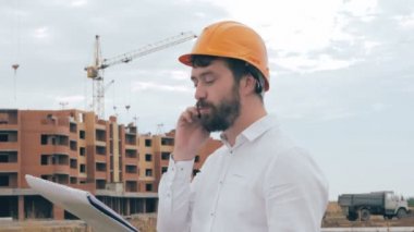 İnşaat alanında cep telefonuyla konuşurken mimar.