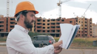 Profesyonel mimar planları, inşaat alanında bakarak.