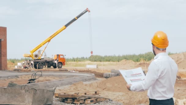 Homme barbu patron de construction vêtu d'un chapeau dur contrôle le processus de construction . — Video