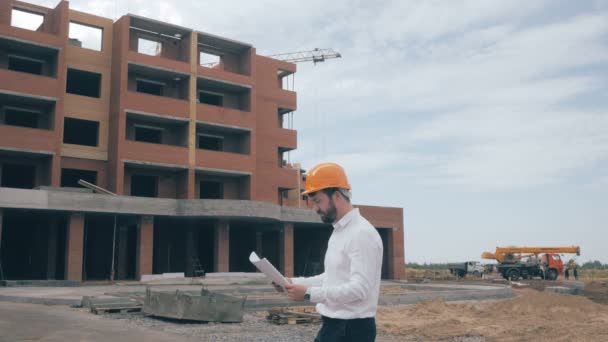 Arquitecto mirando planos en un sitio de construcción . — Vídeo de stock