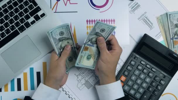 Man in suit counting banknote money US dollars sitting at office workplace. Graphs, laptop, calculator on a table. — Stok video