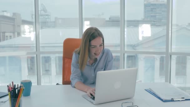 Giovane donna d'affari bella seduta a un tavolo in ufficio moderno che lavora su computer portatile, sorridente . — Video Stock