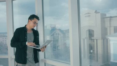 Modern parlak ofiste dizüstü bilgisayarda çalışan adam genç moda.