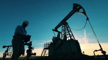 Petrol pompası yakınında çalışan ve dizüstü bilgisayarda yazan bir mühendis.