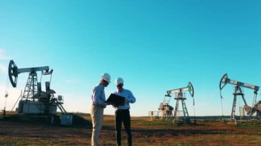 Petrol sahası ekipmanlarını denetleyen iki mühendis.