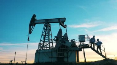 Petrol pompasında petrol sahası düzenlemesini tartışan iki mühendis.