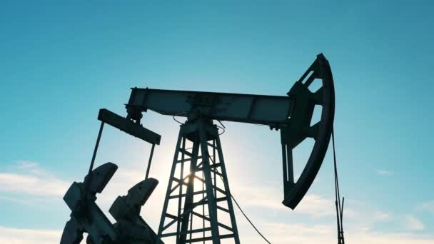 Повільний рух нафтового насоса на нафтовому родовищі проти блакитного неба — стокове відео