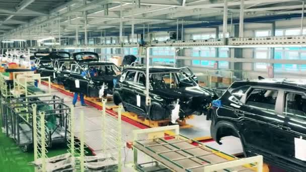 Mitarbeiter der Fabrik arbeiten mit unfertigen Autos. Automobil, Autofabrik Förderband. — Stockvideo