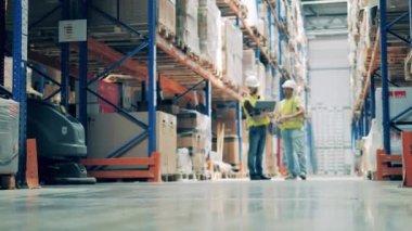 İşçilerle dolu bir depo ve temizlikçiye yön gösteren bir sayborg.