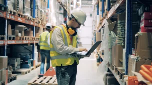 Almacén y dos ingenieros trabajando con los artículos — Vídeo de stock