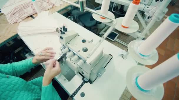 Tovární dělník používá šicí stroj k výrobě kalhotky — Stock video