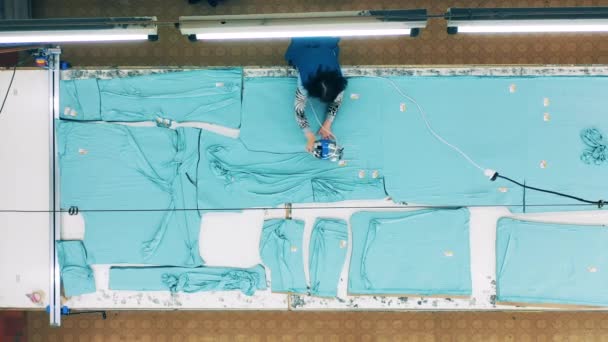 Vista superior de um trabalhador de fábrica usando uma máquina para cortar tecido — Vídeo de Stock