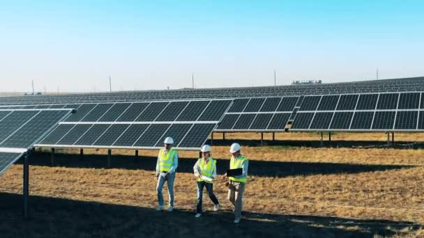 Drie ingenieurs bespreken zakelijke kwesties in de zonnecentrale. Alternatieve energie, concept hernieuwbare elektriciteit. — Stockvideo