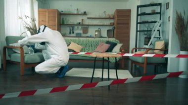 Coronavirus, COVID-19 önleme konsepti. Tehlikeli madde giysisi uzmanı evde mobilyaları temizliyor.