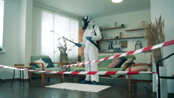 Un hombre con un traje de materiales peligrosos está rociando productos químicos en el apartamento. Coronavirus, concepto de prevención COVID-19. — Vídeos de Stock