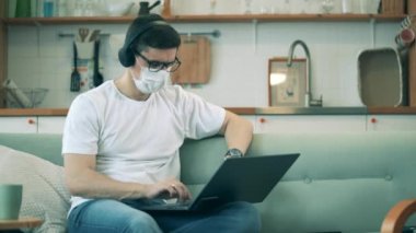 Yüz maskeli bir adam evden çalışmak için aletler kullanıyor. Covid-19 Coronavirus salgını sırasında evde çalışan bir adam..