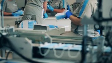 Yüz maskesi üreten işçilerle dolu bir fabrika. Covid-19 önleme üretim süreci.