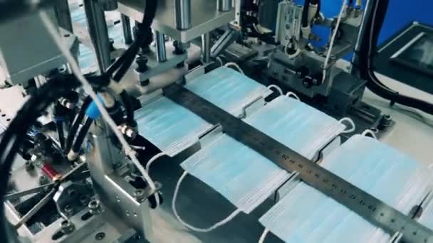 El transportador de fábrica une elásticos a las máscaras faciales — Vídeo de stock