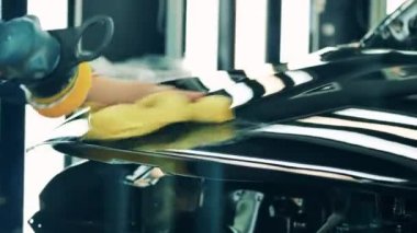 Araba fabrikası işçisi araba cilalıyor.