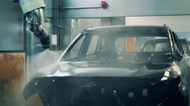Robot silah spreyi araba imalat fabrikasında bir araç cesedi boyuyor.