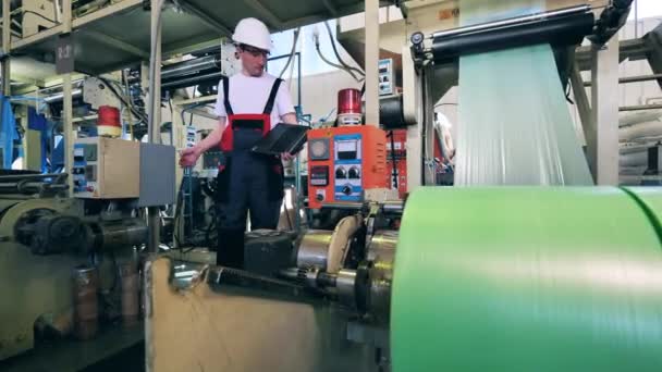 Maszyna fabryczna produkuje folie polietylenowe pod kontrolą pracowników — Wideo stockowe
