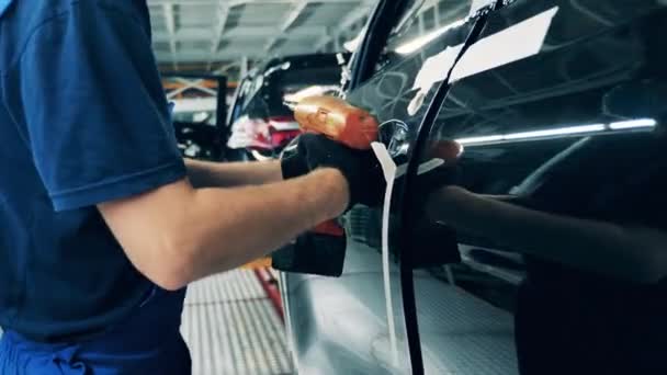 Trabajador de fábrica de automóviles ensamblando una manija de puerta de coche — Vídeo de stock