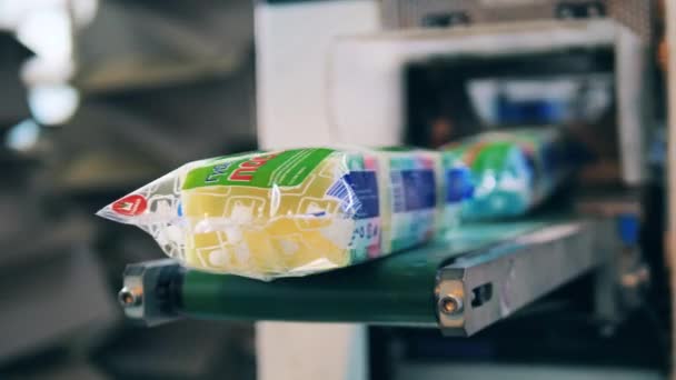 Proses pengepakan di pabrik industri. Kantong plastik dengan spons dapur jatuh dari konveyor — Stok Video