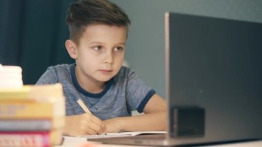 Evde bilgisayar başında ders çalışan küçük bir çocuk.