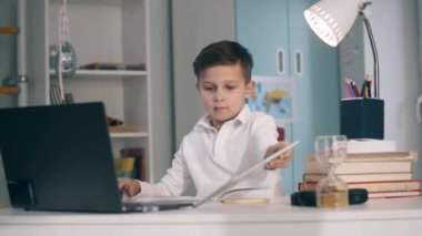 Küçük okul çocuğu bilgisayarını ve tabletini kullanarak uzaktan çalışıyor.