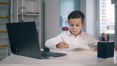 Bilgisayarını kullanarak internetten ders çalışan küçük çocuk.