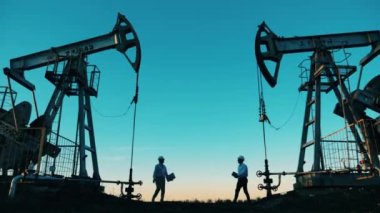 Elektrik işçileri iki pompa arasında toplanıyor. Fosil yakıt, ham petrol konsepti.
