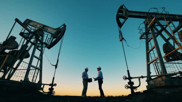 Duas macacos com engenheiros a apertar as mãos entre eles. Combustível fóssil, conceito de petróleo bruto. — Vídeo de Stock