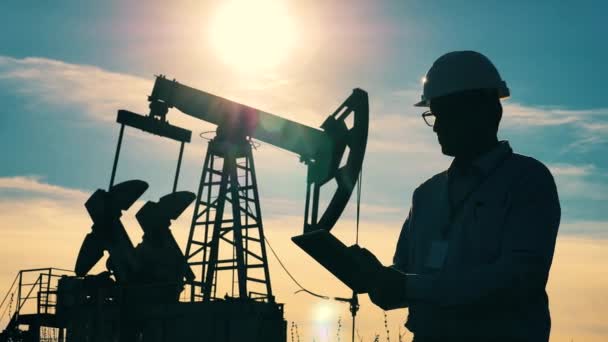 Combustible fósil, concepto de petróleo crudo. Power worker está observando un sitio de extracción de aceite y operando una tableta — Vídeo de stock