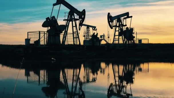 Puesta de sol en el sitio de desarrollo de petróleo con un río cercano. Petróleo crudo, gas, concepto de precios del petróleo. — Vídeo de stock