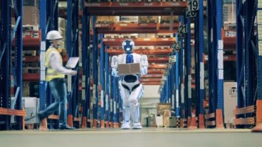 Teslimat robotuyla çalışan bir depo işçisi.